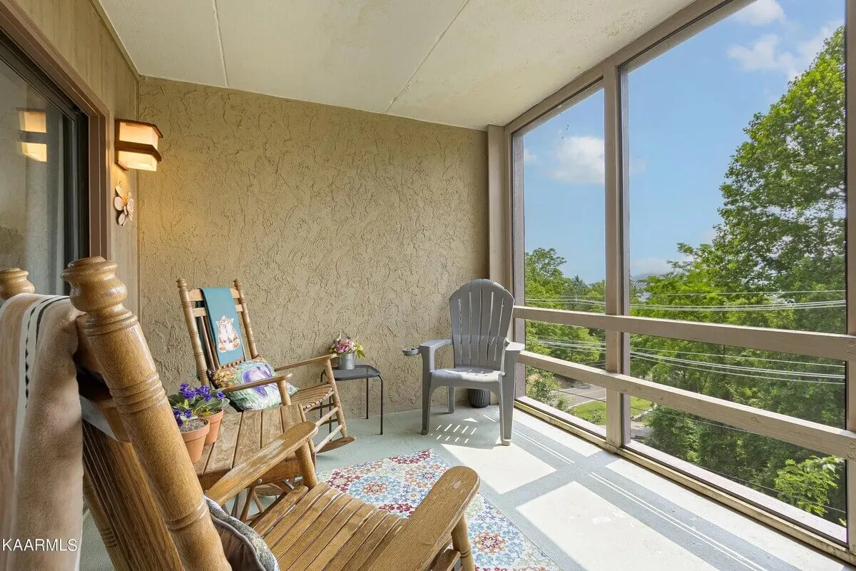 A cozy outdoor seating area with rocking chairs and an Adirondack chair, surrounded by flower pots and decorative wall art. Warm light fills the space, inviting relaxation and moments of togetherness.